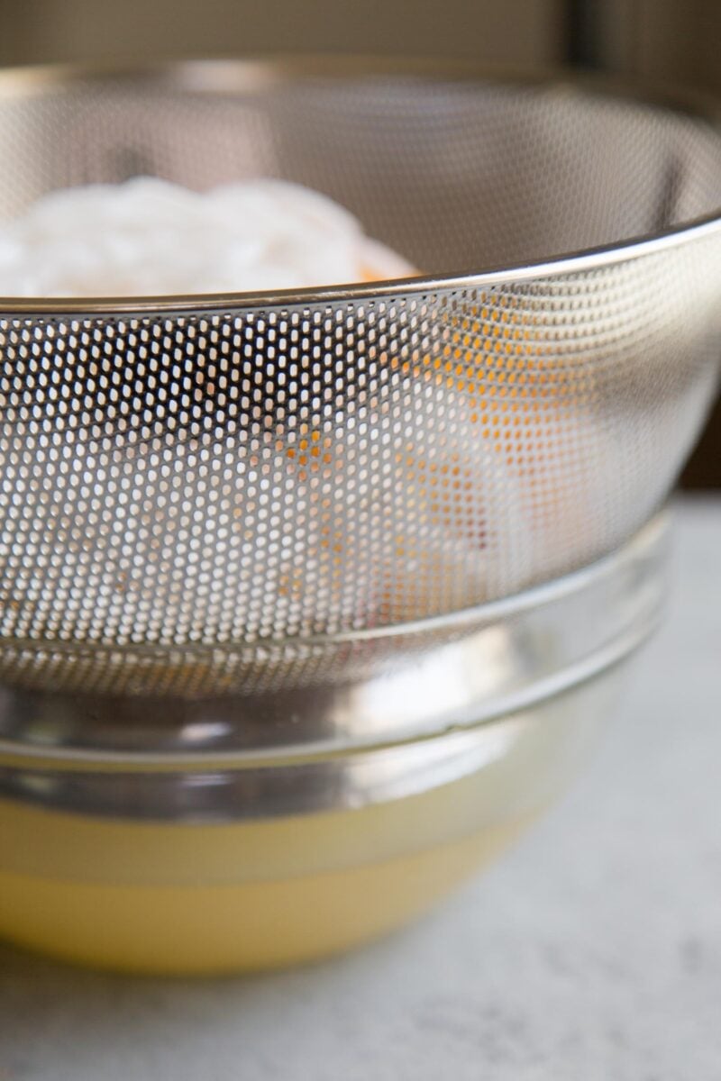 colander filled with fruit cocktail mix set over bowl.