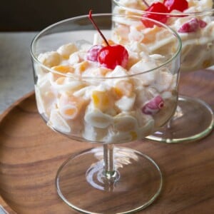 Filipino fruit salad topped with maraschino cherry served in stemmed glass.
