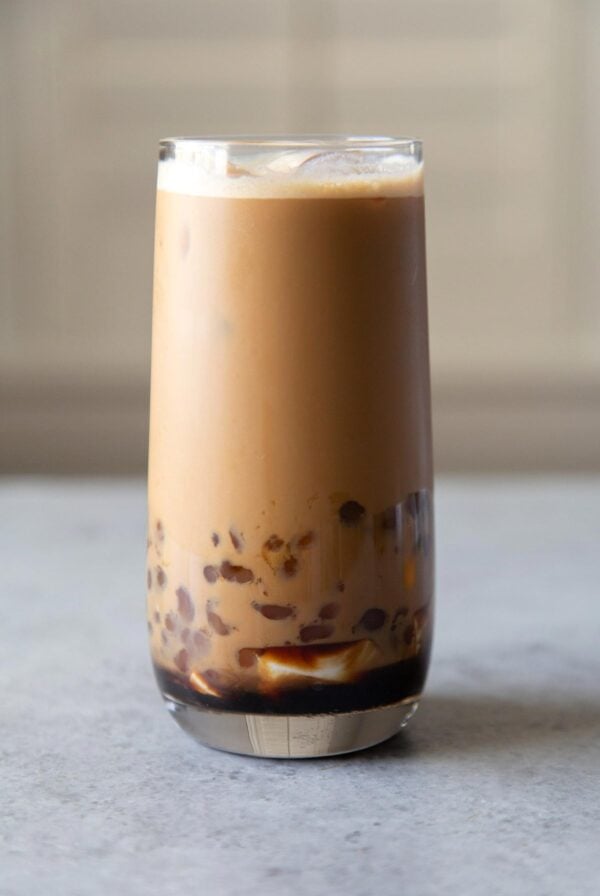 tall glass filled with milk coffee, tapioca pearls, and silken tofu.