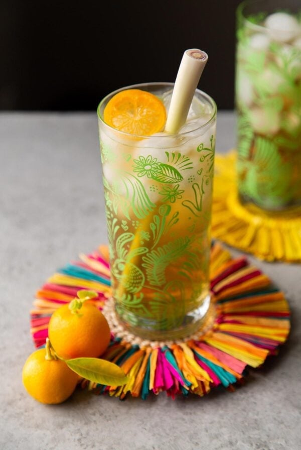 colorful coaster with tall glass filled with lemongrass tea garnished with calamansi wheel.