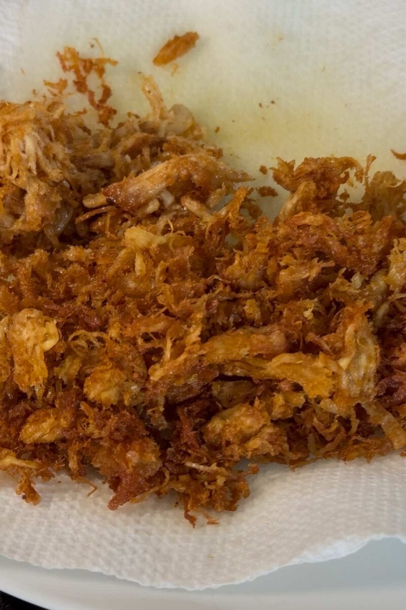 drained fried chicken on paper towel lined plate.