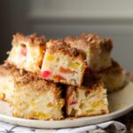 slices of tropical fruit cocktail coffee cake stacked on each other on serving plate.